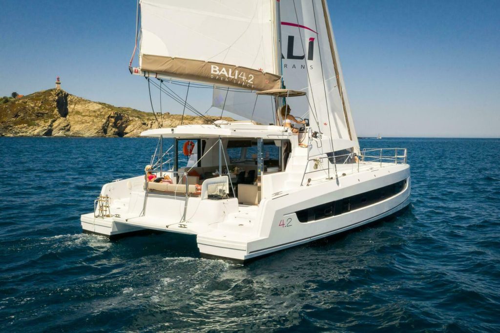 Bali 4.2 catamaran under way, showing the flybridge helm, bimini and solid foredeck